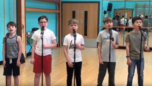 5 drenge stiller sig op, for at synge deres version af en sang fra en kendt musi
